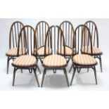 A set of seven Ercol dark elm dining chairs (including one carver) with spindles to the hooped