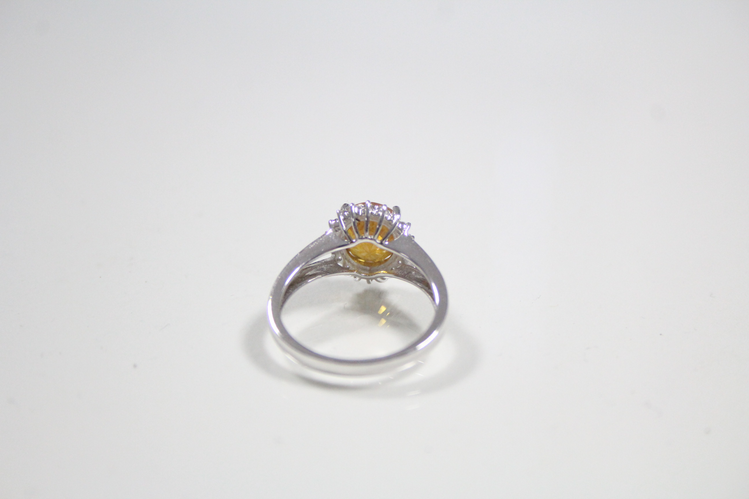 A white 14K ring set yellow-orange oval-cut sapphire within a boarder of small diamonds. - Image 3 of 3