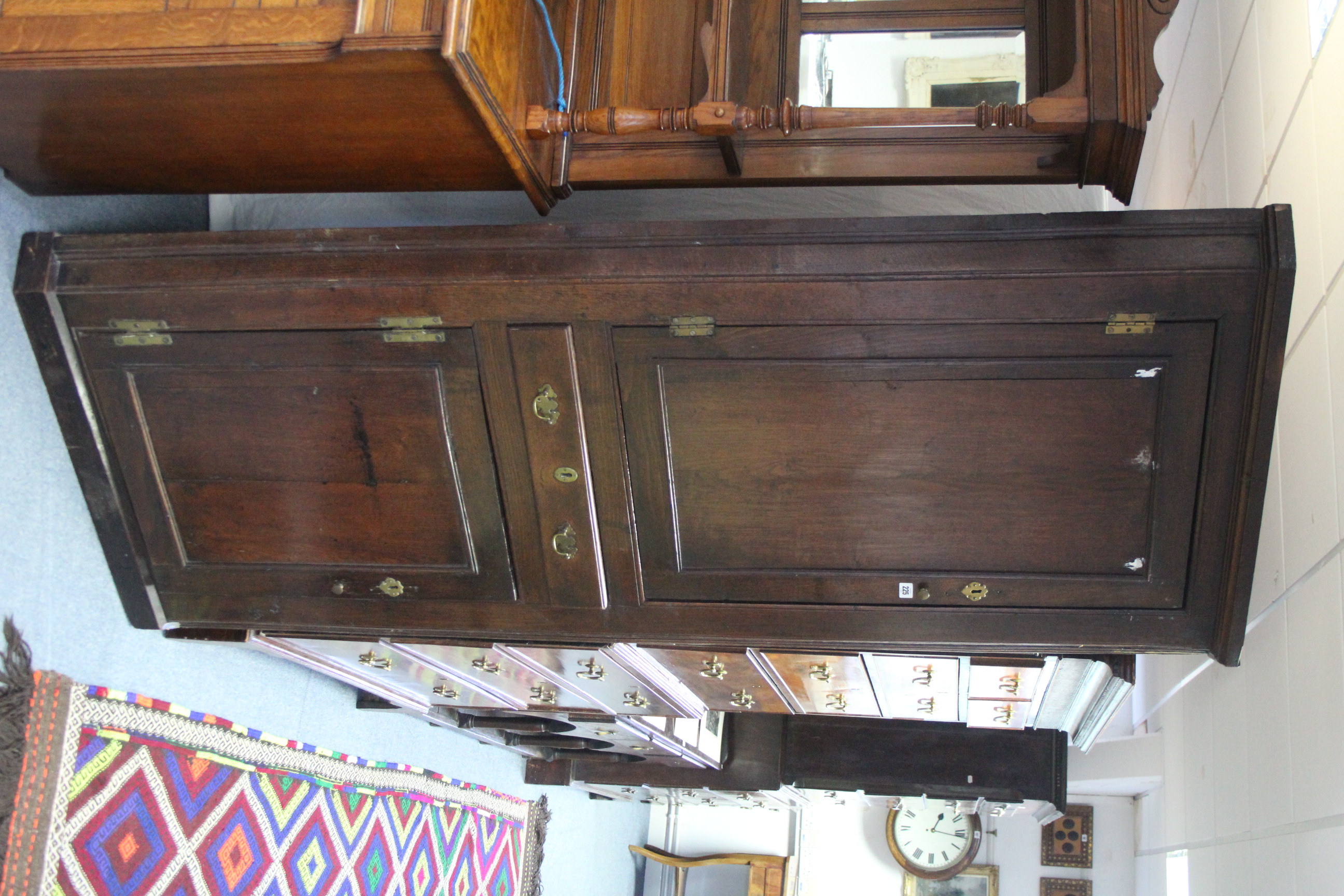 An 18th century oak standing corner cupboard with three shaped shelves to the top enclosed by