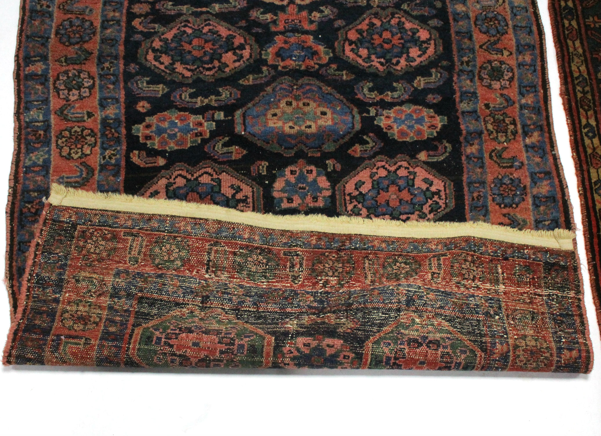 A Persian rug of dark blue ground, pink, blue, & ivory figured with abstract motifs within narrow - Image 2 of 3