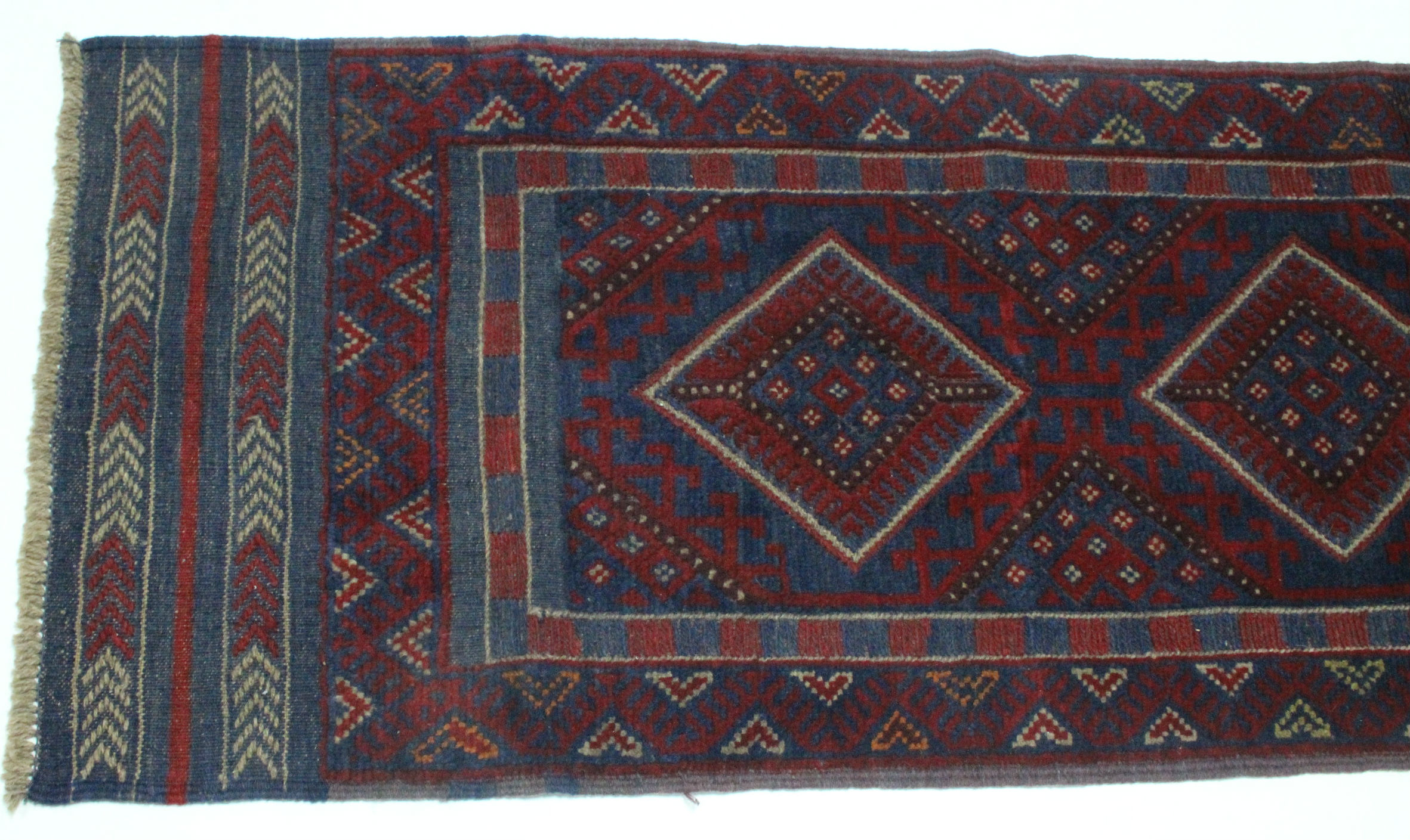 A Meshwari runner of crimson ground, with row of four lozenges to the centre in blue & ivory, wide