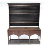 AN 18th century OAK DRESSER, with open shelves above, the base fitted three frieze drawers above a