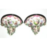 A pair of Dresden porcelain wall brackets in the Meissen style, with cherub supports, painted