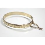A 9ct. gold & metal-core stiff hinged bangle with engraved decoration to one half.
