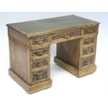 A late 19th/early 20th century carved oak ‘green-man’ pedestal desk inset gilt-tooled leather