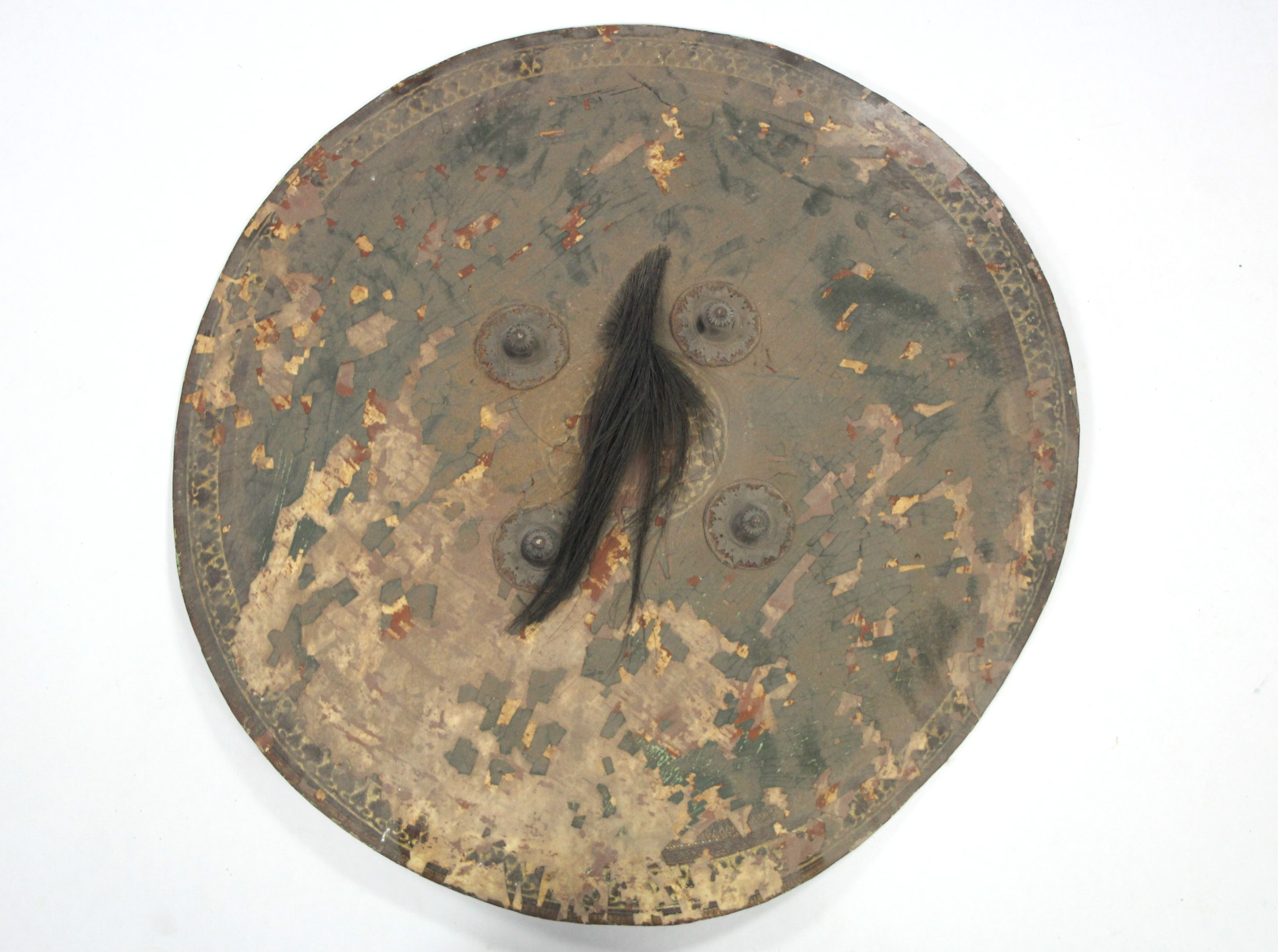 An eastern leather circular shield with four metal bosses & a hair-tuft to the centre; 26" diam.