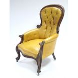 A mid-Victorian carved mahogany frame buttoned-back armchair upholstered brass-studded mustard