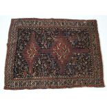 A Persian rug of dark blue ground with double cross motif to centre & on a ground of flowers &