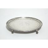 A George III oval teapot stand with beaded rim & engraved floral narrow border, on four claw-&-