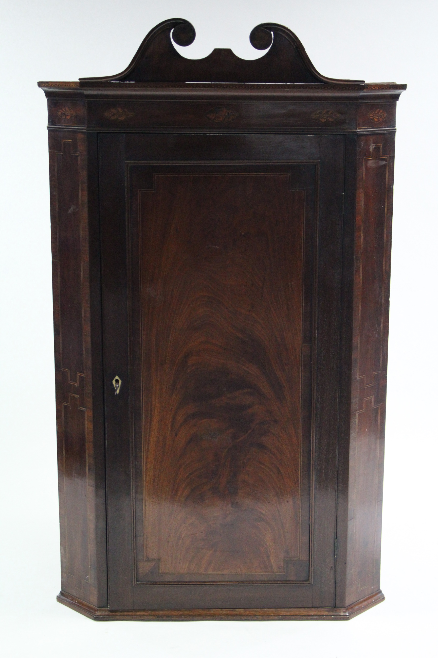 A late 18th century figured mahogany hanging corner cupboard with swan-neck pediment, marquetry