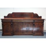 A mid-Victorian mahogany sideboard with carved raised back, fitted three frieze drawers above a