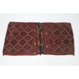 A tribal large double-sided saddle bag with repeating lozenge design in rust-red, blue, fawn, &