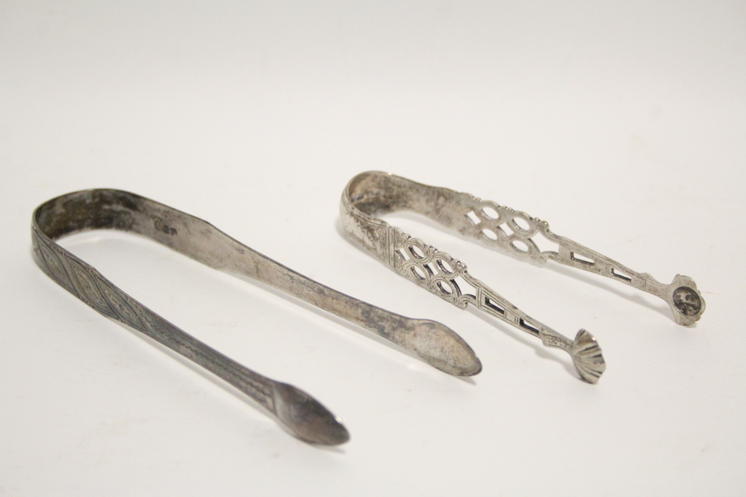 A pair of Victorian sugar tongs in the mid-18th century style, with pierced stems & shell bowls,