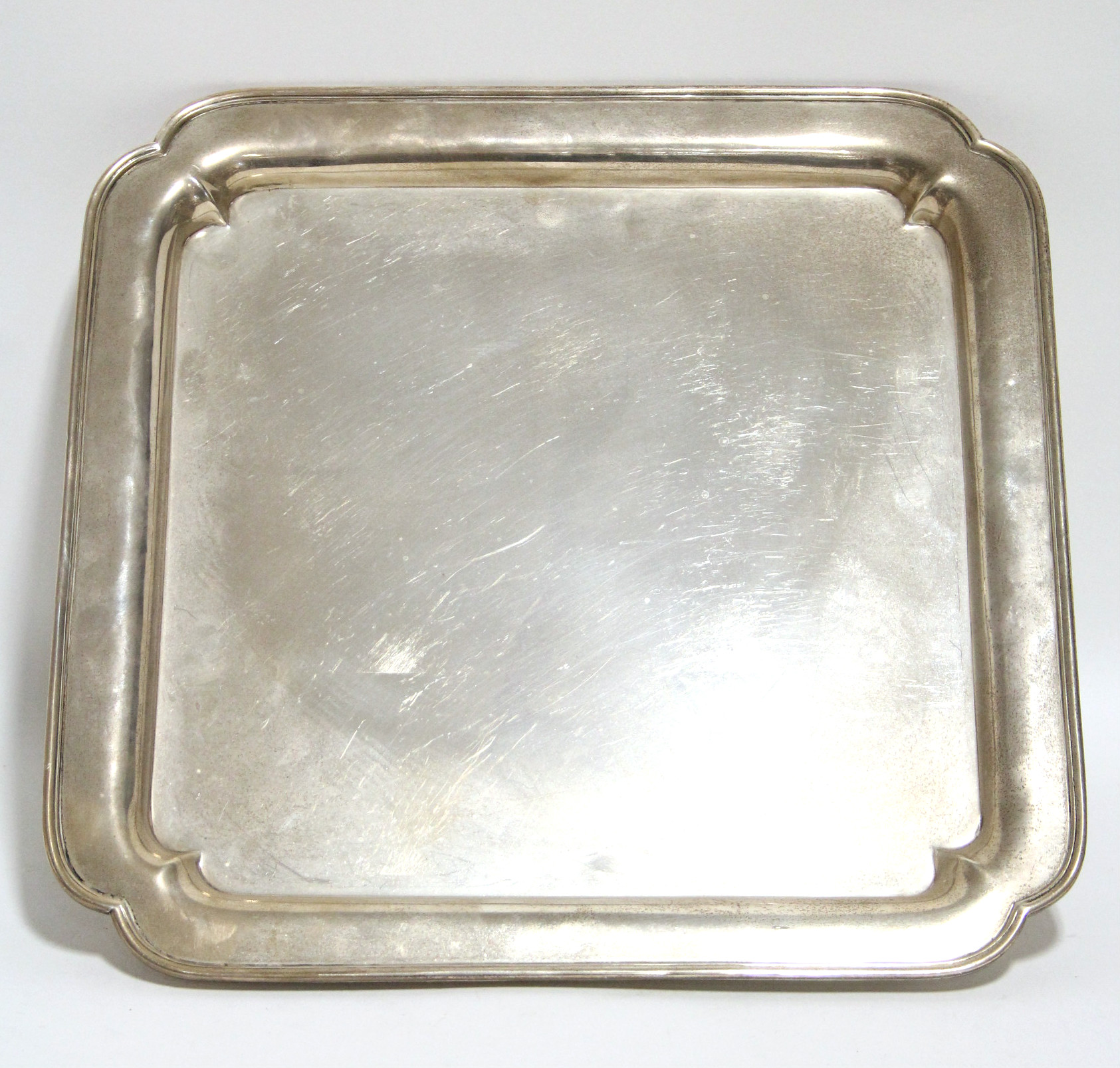 A George V heavy-gauge square tray with re-entrant corners & moulded rim to the raised border, on