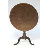 An 18th century oak tripod table, the circular tilt-top on vase-turned centre column & three