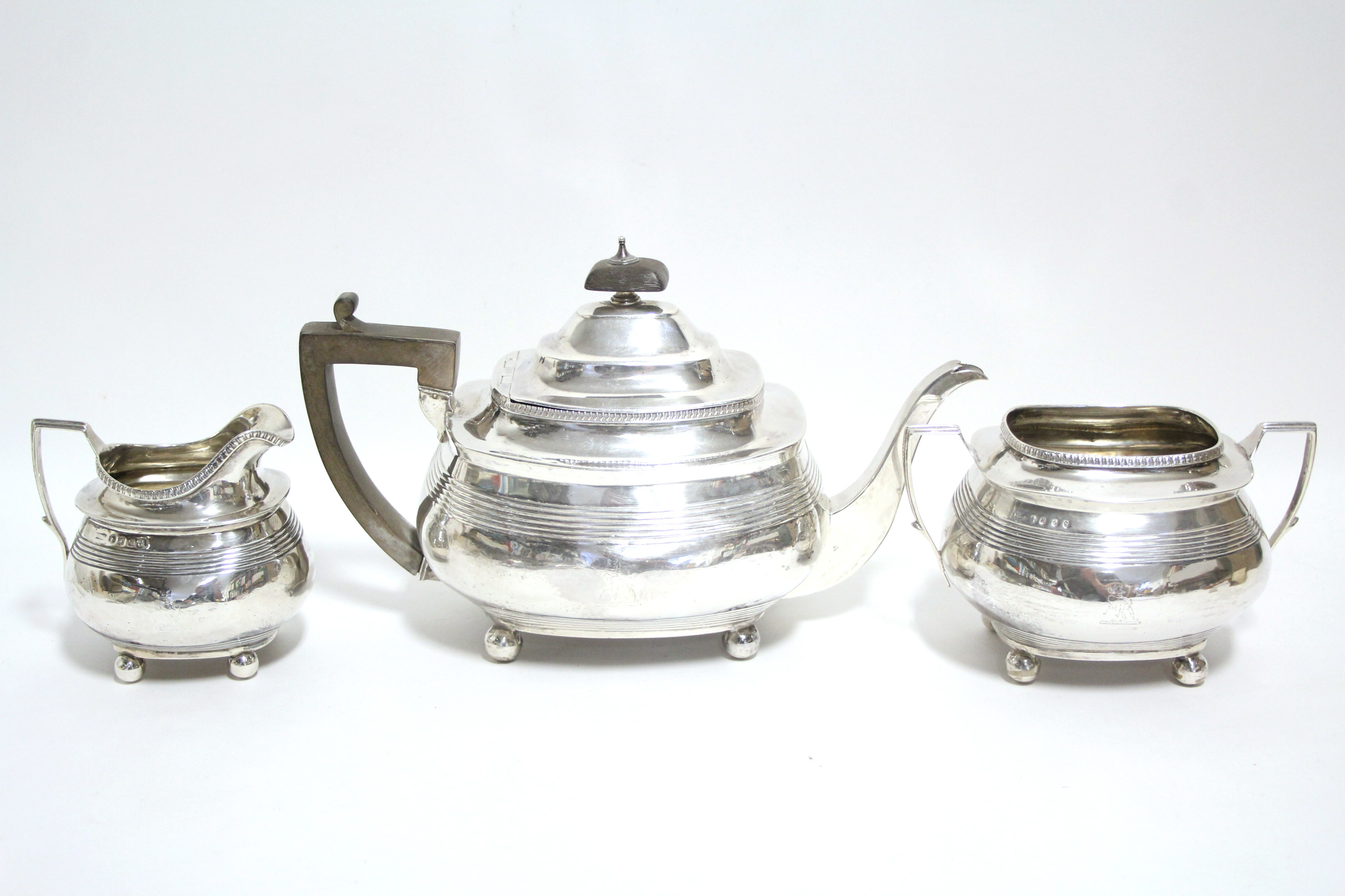 A George II teapot of compressed oblong form with reeded bands, on four ball feet, London 1810, by