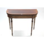 A regency mahogany crossbanded card table inset crimson baize to the rectangular fold-over top &