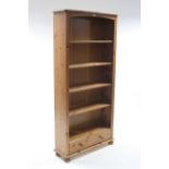 A pine tall standing open bookcase with four adjustable shelves above a long drawer, & on turned