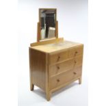 A mid-20th century light oak dressing chest with rectangular swing mirror to the stage back,