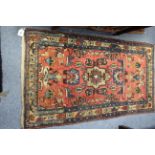A Persian rug of crimson & blue ground & with all-over repeating multi-coloured geometric design,