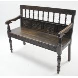 A carved oak hall bench with spindle-rail to back, with hard seat & on turned tapered legs, 43”