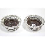 A pair of silver plated coasters with raised vine-leaf borders, & with carved treen bases, 6¾”