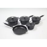 A set of three Le Creuset black graduated saucepans; a ditto casserole dish; & a ditto frying pan.