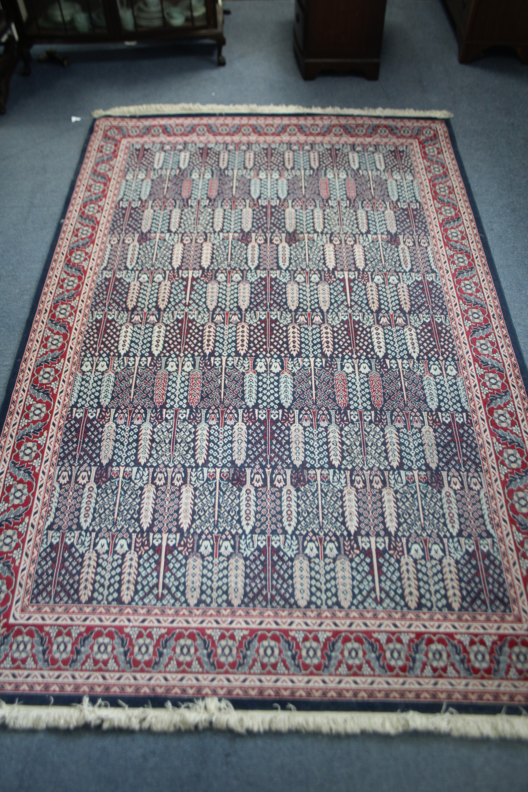 A small carpet of crimson & blue ground & with all-over repeating multi-coloured geometric design to