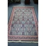 A small carpet of crimson & blue ground & with all-over repeating multi-coloured geometric design to