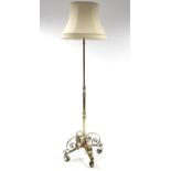 An Edwardian brass standard lamp with telescopic centre column & on four shaped supports, with
