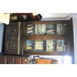 A 1920’s oak tall standing bookcase with three adjustable shelves enclosed by pair of leaded