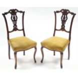 A pair of early 20th century carved beech occasional chairs with padded seats, & on slender cabriole