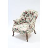 A Victorian buttoned-back easy chair upholstered multi-coloured floral material, & on short turned
