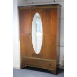 An Edwardian inlaid-mahogany wardrobe enclosed by bevelled oval mirror door to centre above a long
