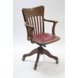 An Edwardian oak lath-back swivel office chair with padded seat, & on four cabriole legs with