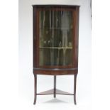 An Edwardian mahogany & satinwood serpentine front standing corner cabinet fitted two shaped shelves