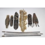 A collection of African artefacts including carved wood masks, spears, bows & arrows, fly-whisks,