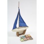 A white painted wooden pond yacht with sails, 18” wide; & six various packs of playing cards.