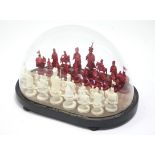 A late 19th/early 20th century carved ivory chess set of natural & red stain, each piece in the form