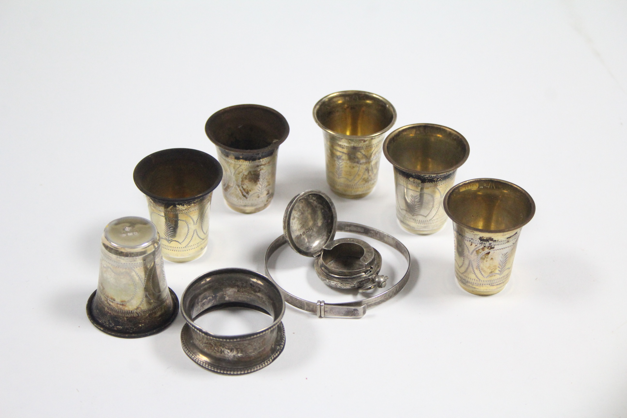 A set of six George V silver engraved shot cups, London 1921; a silver sovereign case; a silver