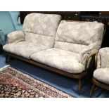 An Ercol elm spindle-back three-seater settee with floral printed cushions to the seat and back, and