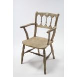 A rustic style spindle-back elbow chair with hard seat, and on turned legs with spindle stretchers.