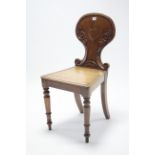 A Victorian mahogany hall chair with carved and shaped back, with hard seat, and on turned tapered