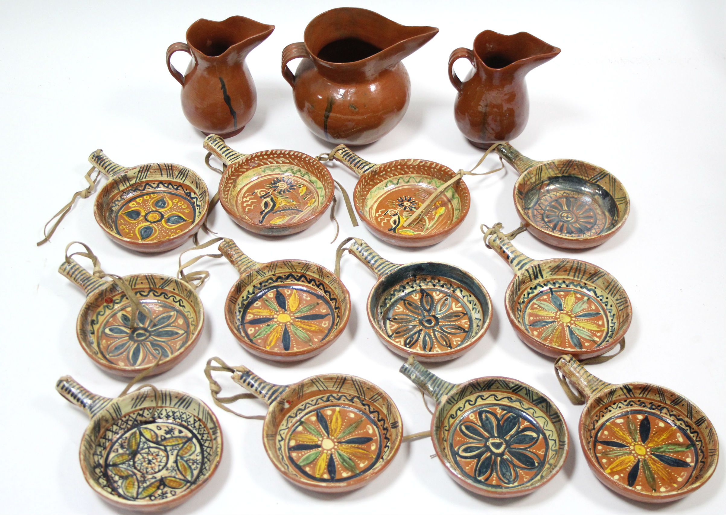 A set of twelve Mexican pottery cooking pans, each with bright-coloured geometric design; a ditto