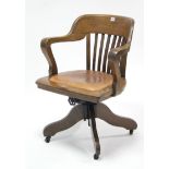 An early 20th century oak lath-back revolving desk chair with padded seat, and on sprung centre