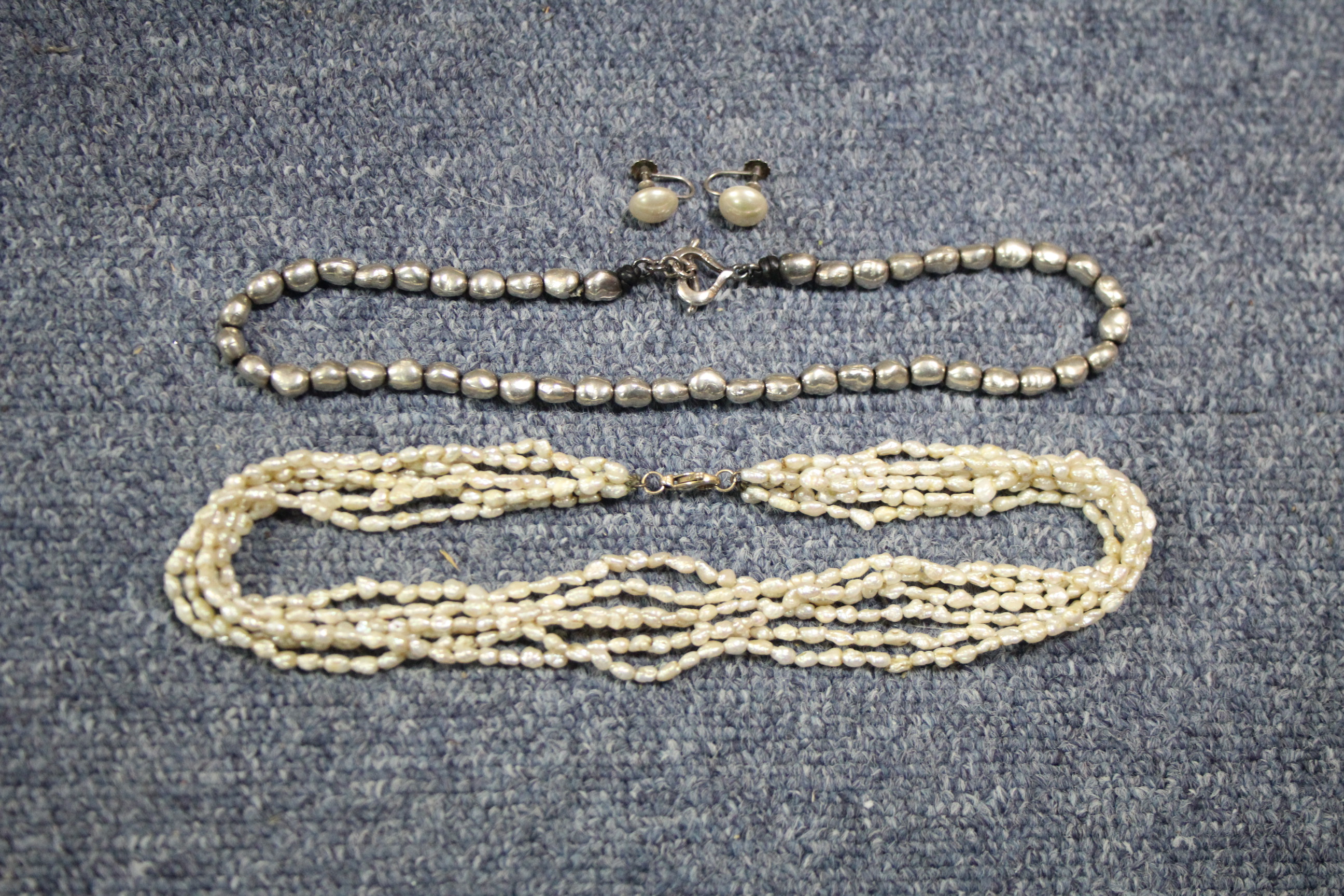 A necklace of silver-coloured metallic beads; a multi-strand necklace of small baroque pearls; & a