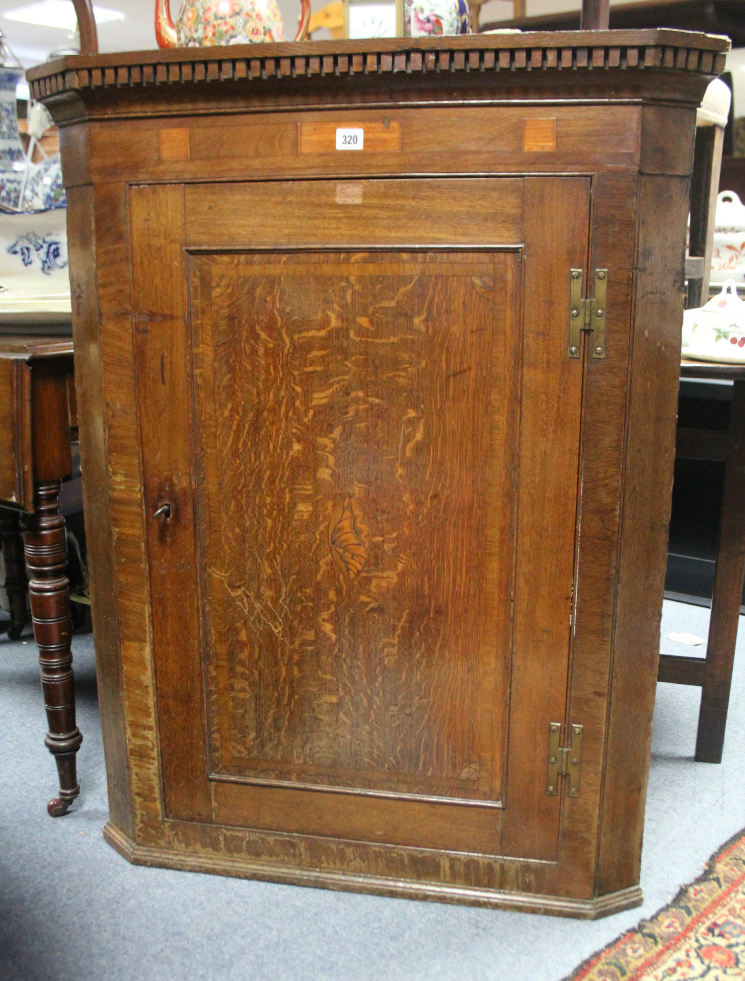 A late 18th century inlaid oak hanging corner cupboard fitted three shaped shelves enclosed by a