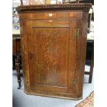 A late 18th century inlaid oak hanging corner cupboard fitted three shaped shelves enclosed by a