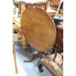 A late 19th/early 20th century oak tripod table, the circular tilt-top on baluster-turned column &