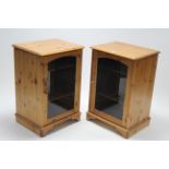 A pair of pine small standing upright cabinets each fitted two shelves enclosed by glazed door,